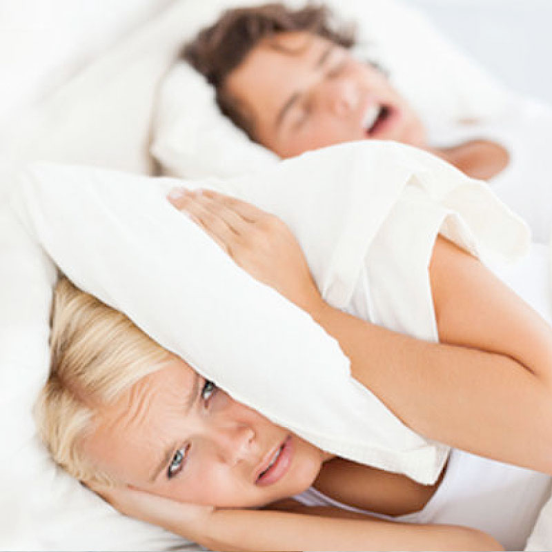 Image of girl blocking ears with pillow from snoring partner